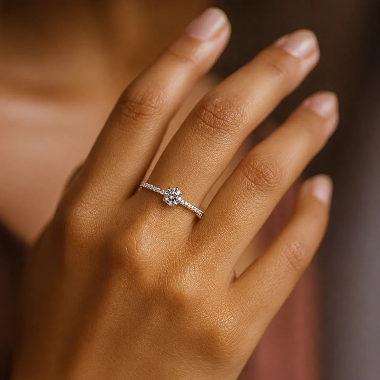 Close-up of a hand wearing a diamond ring with a blurred background